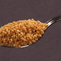 Sarvaay Organic Jaggery Powder on a spoon showing natural texture